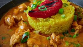 Butter Chicken Curry mit Kurkuma-Reis serviert.