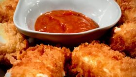 Panierte Feta-Käse-Streifen in Öl frittiert und mit einer BBQ-Sauce serviert.