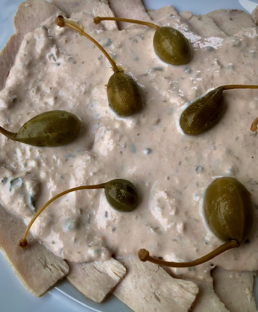 Vitello Tonnato mit einer leichten Joghurt Sauce auf einem Teller mit Kapern angerichtet.