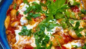 Gebackene Bohnen in Tomatensauce, in einer Schale mit frischer Petersilie garniert.