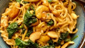 Gebratene Mie-Nudeln mit Spinat und gerösteten Cashewkernen in einer Schüssel serviert.
