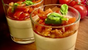 Servierfertige herzhafte Parmesan Panna Cotta mit fruchtigem Tomaten-Topping und frischen Kräutern als appetitanregender Gruß aus der Küche.