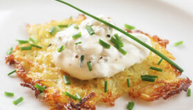 Rösti Hüttenzauber, mit frischem Schnittlauch auf einem weißen Teller serviert.
