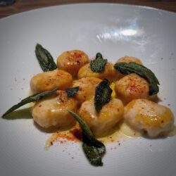 Kürbis-Ricotta-Gnocchi auf einem weißen Teller angerichtet und mit Salbeiblätter dekoriert