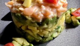 Lachstartar mit Avocado und Mango auf einem grauen Steinteller serviert.