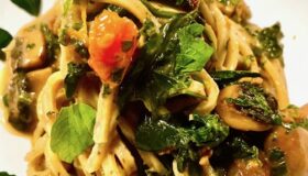 Linguine mit getrüffelten Champignons auf einem hellen Teller serviert und mit frischen Kräutern garniert.