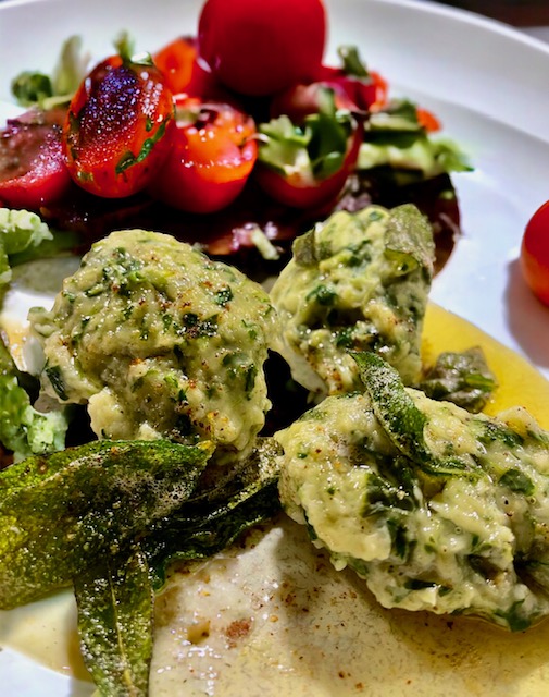 Malfatti in Salbeibutter auf einem hellen Teller angerichtet.