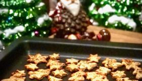 Herzhafte Parmesan Plätzchen in Stern- und Tannenbaumform auf dem Harecker Backblech vor weihnachtlicher Dekoration.