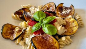 Pasta mit Auberginencreme und frittierten Auberginen auf einem hellen Teller angerichtet.