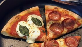 Eine frisch wie frisch gebackene und aufgewärmte Pizza in einer Harecker Pfanne mit Decker auf einem Cerankochfeld.