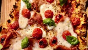 Pizza mit Mozzarella und Parmaschinken belegt.