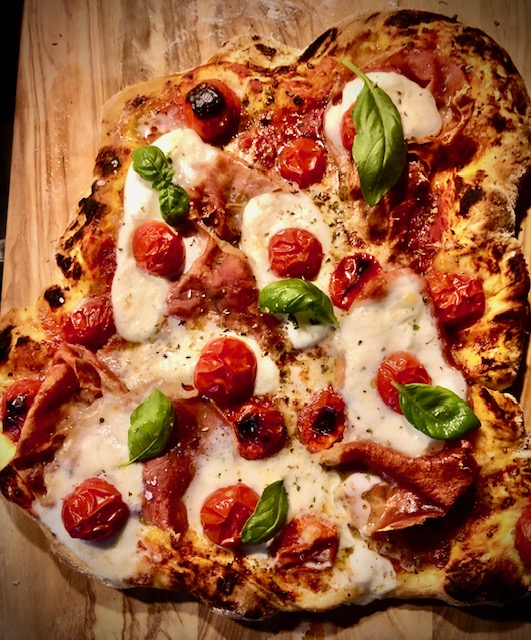 Pizza mit Mozzarella und Parmaschinken belegt.