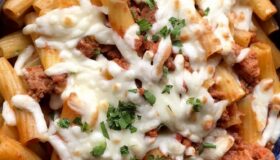 Rigatoni al forno mit Ragout aus Salsiccia auf einem Teller angerichtet.
