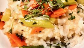 Risotto mit frischem grünem Spargel und Kartoffeln dekorativ auf einem weißen Teller angerichtet.
