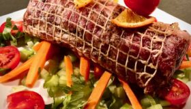 Rollbraten mit mediterranen Zutaten auf einem hellen Teller serviert.