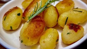 Eine weiße Schüssel mit Kartoffeln und Rosmarinzweigen, serviert als Beilage.