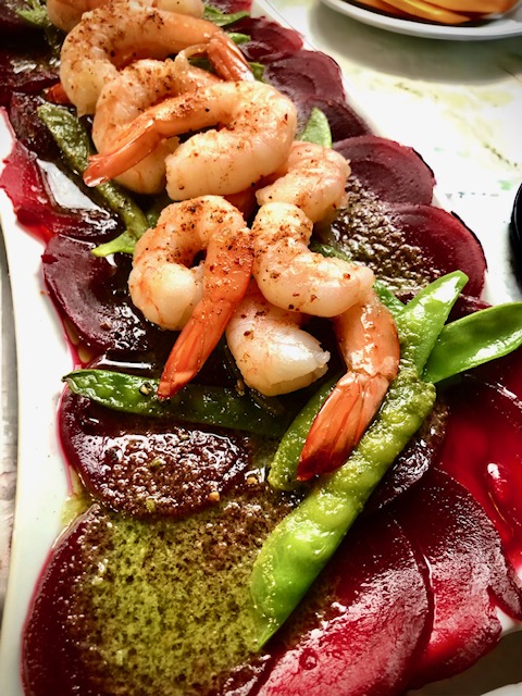 Rote Beete Carpaccio mit Shrimps und Zuckerschoten auf einem weißen Teller serviert.