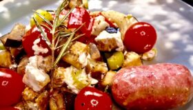 Salsiccia mit Gemüse aus dem Ofen und auf einem beigen Teller serviert.