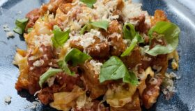 Salsiccia-SpitzkohlPfanne (neu) auf einem dunklen Teller angerichtet und mit Parmesan und Basilikum dekoriert.