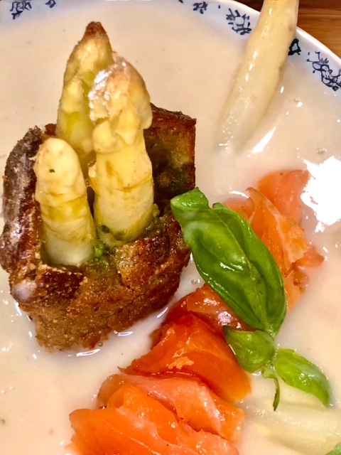 Spargelcremesuppe mit Räucherlachs in einer Schale seviert.