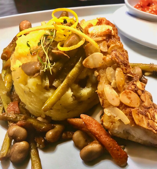 Knuspriger Zander mit Mandeln paniert und herrlich duftenden Kartoffelstampf der mit etwas Trüffel verfeinert wurde auf einem Teller
 mit Bohnengemüse.